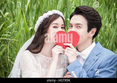 Ritratto di giovane coppia romantica con cuore contro erba verde Foto Stock