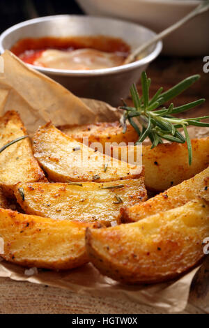 Patate arrosto con dip sul tavolo di legno Foto Stock