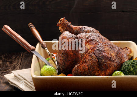 Tutto il pollo arrosto con verdure in vaso su sfondo di legno Foto Stock