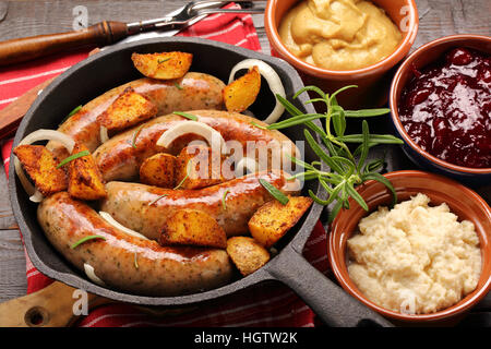 Salsicce bianche con patate al forno in padella Foto Stock