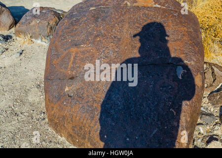 Fotografo ombra con incisioni rupestri pecked in basaltat BLM il punto Grimes Area Archeologica di Fallon, Nevada, STATI UNITI D'AMERICA Foto Stock