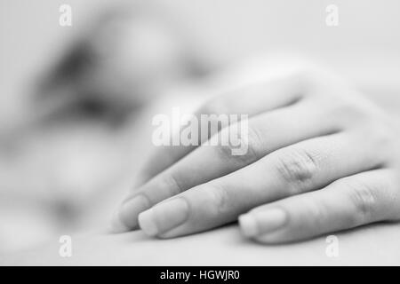 Giovani womans mano sulla gamba in bianco e nero Foto Stock