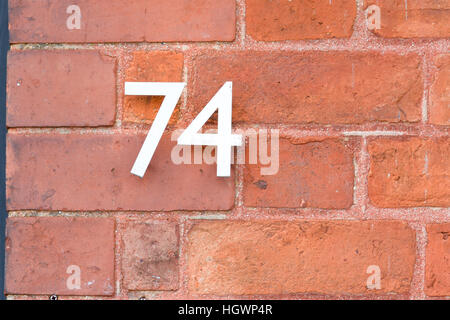 Il numero civico 74 segno rosso sul muro di mattoni Foto Stock