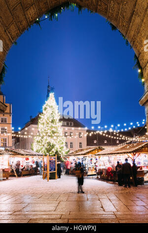 Vista della piazza del Municipio - Raekoja Plats attraverso l'arco di Town Hall a Tallinn in Estonia. Albero di natale e case commerciali con vendita di Christm Foto Stock