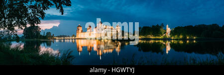 Mir, Bielorussia. Scenic Vista panoramica del complesso del Castello di Mir In illuminazione serale dal lato del lago. Famoso punto di riferimento, antico monumento in Blue di DRAM Foto Stock