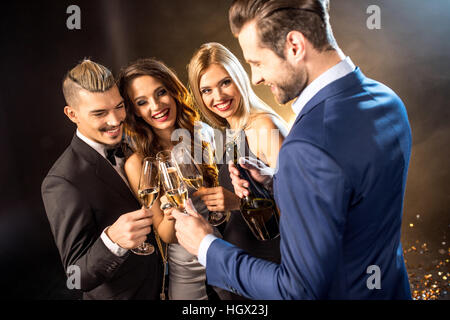 Felice giovani amici bevendo champagne e bicchieri tintinnanti Foto Stock