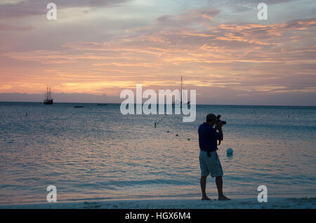 Aruba, dei Caraibi - Settembre 25, 2012: Fotografo al tramonto con ancorate le barche a vela sul mare dalla baia. L'immagine è stata scattata in Aruba, in auto Foto Stock