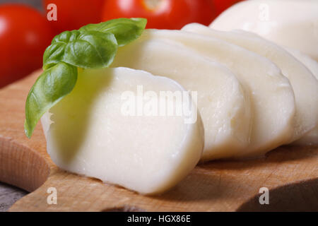 Macro fette di mozzarella con basilico sulla scheda di cucina Foto Stock