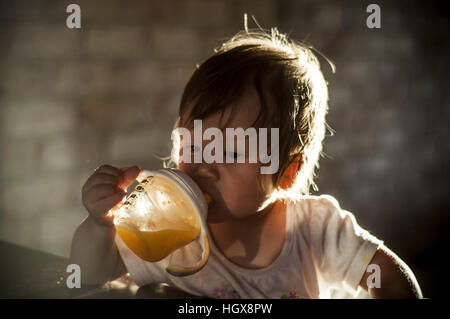 Baby girl bere il succo d'arancia Foto Stock