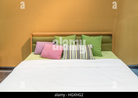 Interiore camera da letto con letto e cuscini colorati di casa accogliente in un design moderno. Camera da letto vintage. Foto Stock