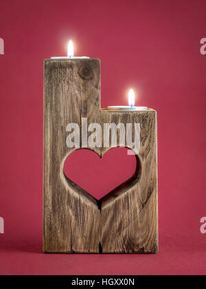 Acceso romantica in legno porta candela con taglio cuore su sfondo rosso Foto Stock