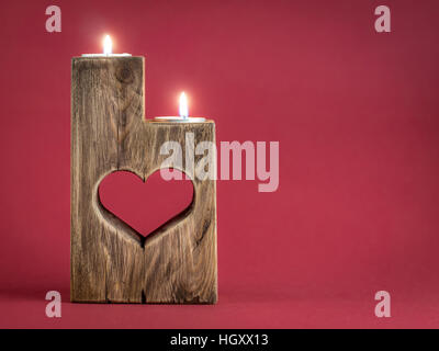 Acceso romantica in legno porta candela con taglio cuore su sfondo rosso Foto Stock