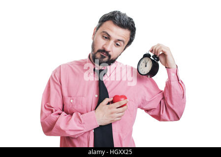 Giovane uomo con la forma di un cuore rosso e sveglia sul suo orecchio Foto Stock