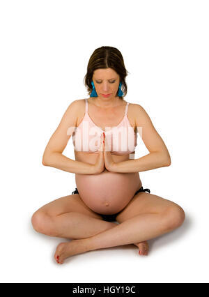 La donna incinta è che esercitano in un yoga sit Foto Stock