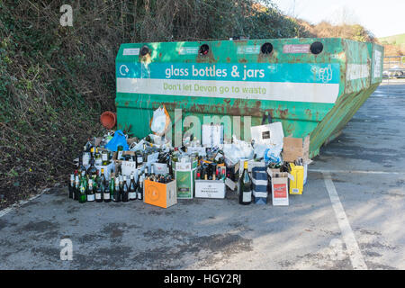 Bottiglia di vetro del contenitore di riciclaggio con bottiglie impilate accanto ad esso Foto Stock