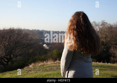 Vista posteriore di una donna in piedi da solo in una posizione tranquilla guardando in lontananza Foto Stock