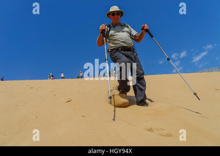 Close up di un uomo anziano con walking correre giù il quasi 49 metri di alte dune di sabbia a salir do Porto, Portogallo Foto Stock