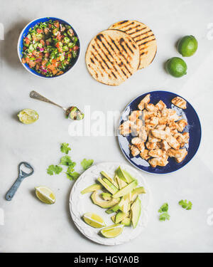 Gli ingredienti per cucinare il pollo e avocado tacos, grigio Sfondo marmo Foto Stock