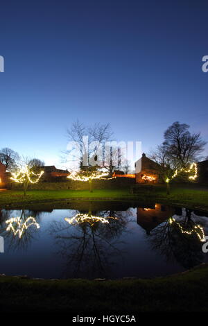 Le luci di Natale intorno al laghetto sul verde in Foolow, Parco Nazionale di Peak District, Derbyshire, England, Regno Unito Foto Stock