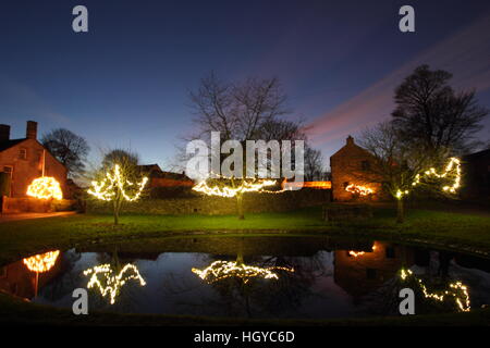 Le luci di Natale intorno al laghetto sul verde in Foolow, Parco Nazionale di Peak District, Derbyshire, England, Regno Unito Foto Stock