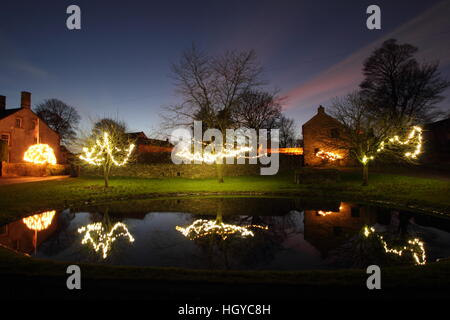 Le luci di Natale intorno al laghetto sul verde in Foolow, Parco Nazionale di Peak District, Derbyshire, England, Regno Unito Foto Stock