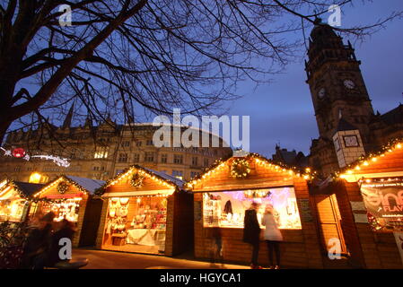 Gli acquirenti di festa sfoglia merci nella cute di cabine di legno al mercatino di Natale sulla Fargate, centro della città di Sheffield nello Yorkshire, Inghilterra Foto Stock
