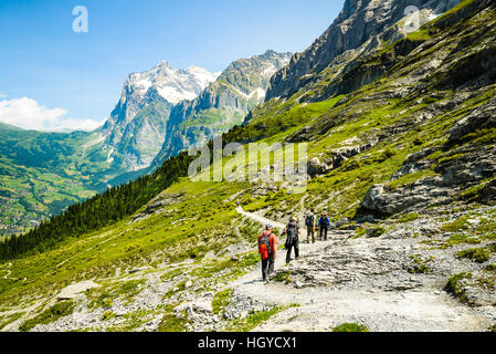 Gli escursionisti sul sentiero di Eiger svizzera con il Grindelwald valle sottostante e il Wetterhorn dietro di picco Foto Stock