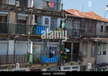 Portogallo: dettagli di strade e vicoli del porto con la vista dei palazzi della città vecchia con un vecchio su un balcone Foto Stock