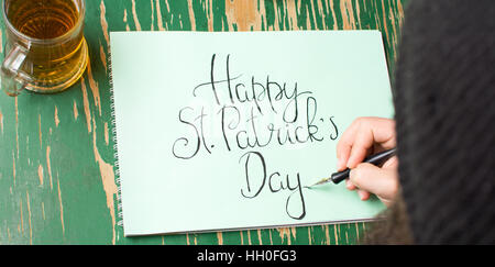 L'uomo la scrittura di un felice St Patrick giorno scheda di calligrafia Foto Stock