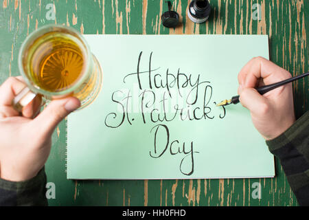 L'uomo con una birra con felice St Patrick giorno scheda di calligrafia Foto Stock