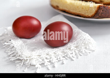 Sul tavolo su un tovagliolo bianco sono due dipinti di uova di Pasqua, accanto alla piastra di fette di torta. Foto Stock