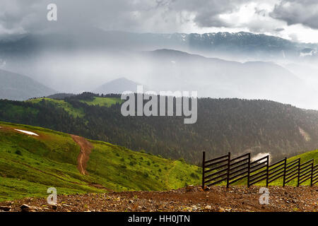 Paesaggio di montagna: ripide montagne coperte di foreste, forma una gola profonda in lontananza si possono vedere le gamme della montagna con nuvole sopra le cime, po Foto Stock
