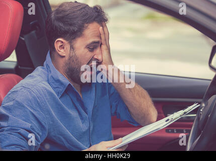 Sottolineato uomo disperato conducente con documenti seduta dentro la sua auto Foto Stock