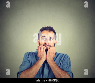 Ritratto ansioso giovane uomo morde i chiodi dita freaking out Foto Stock