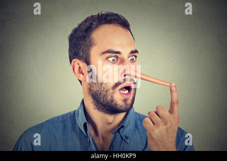 Uomo con il naso lungo isolato sul muro grigio Sfondo. Concetto bugiardo. Volto umano espressioni, emozioni, sentimenti. Foto Stock