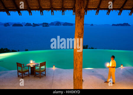 Six Senses Resort Koh Yao Noi, Phang Nga Bay, Thailandia, in Asia. Cameriere con candele nel ristorante vicino alla piscina chiamato collina Reser Foto Stock