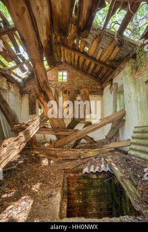 Disastro di Chernobyl. L'interno della rovina dei abbandonato casa di campagna privata con tetto sfondato in Area di esclusione dopo terribili conseguenze del Nuclea Foto Stock