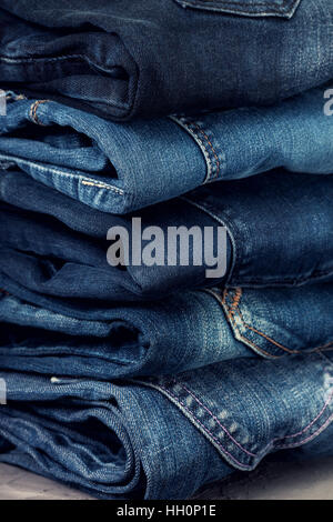 Pila di jeans blu su un cemento grigio sfondo Foto Stock