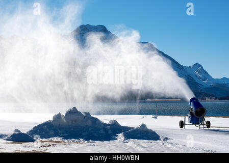 Neve artificiale soffiata da neve pistola in piedi vicino all acqua sul terreno snowbound in giornata soleggiata con cielo blu Foto Stock