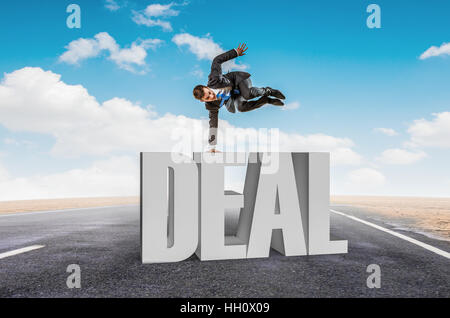 Giovane imprenditore allegro facendo handstand sulla parola DEAL Foto Stock