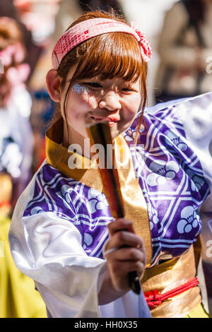Yosakoi giapponese festival. Giovane donna danza, con tinte capelli arancione, vicino, mantenendo la ventola e sorridente con la luce del sole sul viso. Contatto visivo. Foto Stock