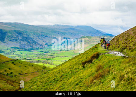 Gli amanti della mountain bike sul famoso sentiero intorno Lonscale cadde nel distretto del lago con Helvellyn nella nuvola in distanza Foto Stock