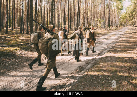 Gruppo di unidentified re-enactors vestito come sovietica soldati russi va lungo la strada forestale. Foto Stock