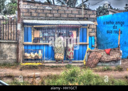 Un generale blu negozio rivenditore realizzato da stagno e mattone., con live polli in gabbia davanti e sarong rivestito di acquirenti. Foto Stock