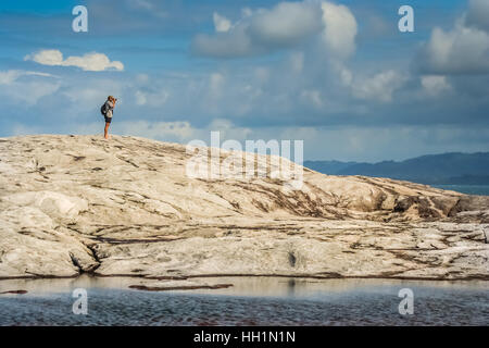 Tourist in piedi su una grande roccia e scattare foto della bellissima costa di Nosy Antafa isola in Madagascar Foto Stock