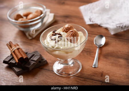 La vaniglia dolce nel bicchiere di vetro decorate con il cioccolato grattugiato e amaretti Foto Stock