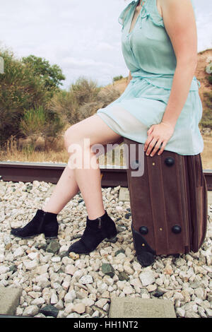 Donna seduta in una valigia vintage Foto Stock