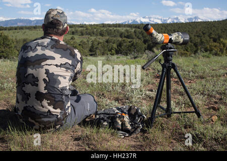 All'aperto uomo seduto vicino al suo cannocchiale guardando al lato del paese nella parte occidentale di Colorado Foto Stock