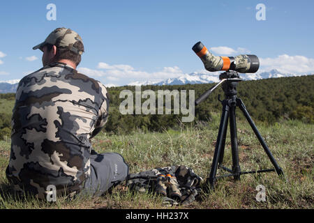 All'aperto uomo seduto vicino al suo cannocchiale guardando al lato del paese nella parte occidentale di Colorado Foto Stock