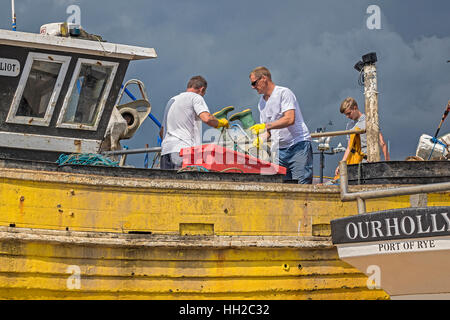 La pulizia delle barche di pescatori sulla spiaggia Hastings Regno Unito Foto Stock